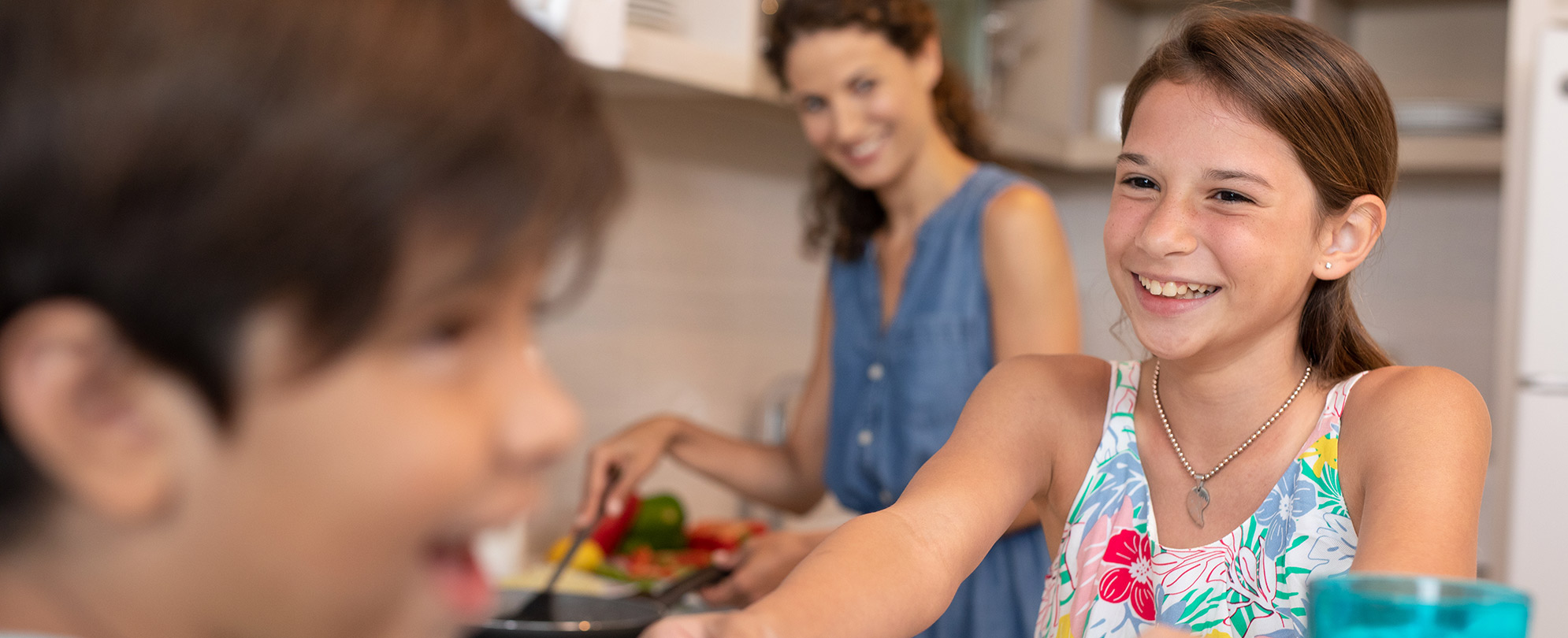 Happy little girl and her brother in the kitchen helping their mother prepare dinner. 