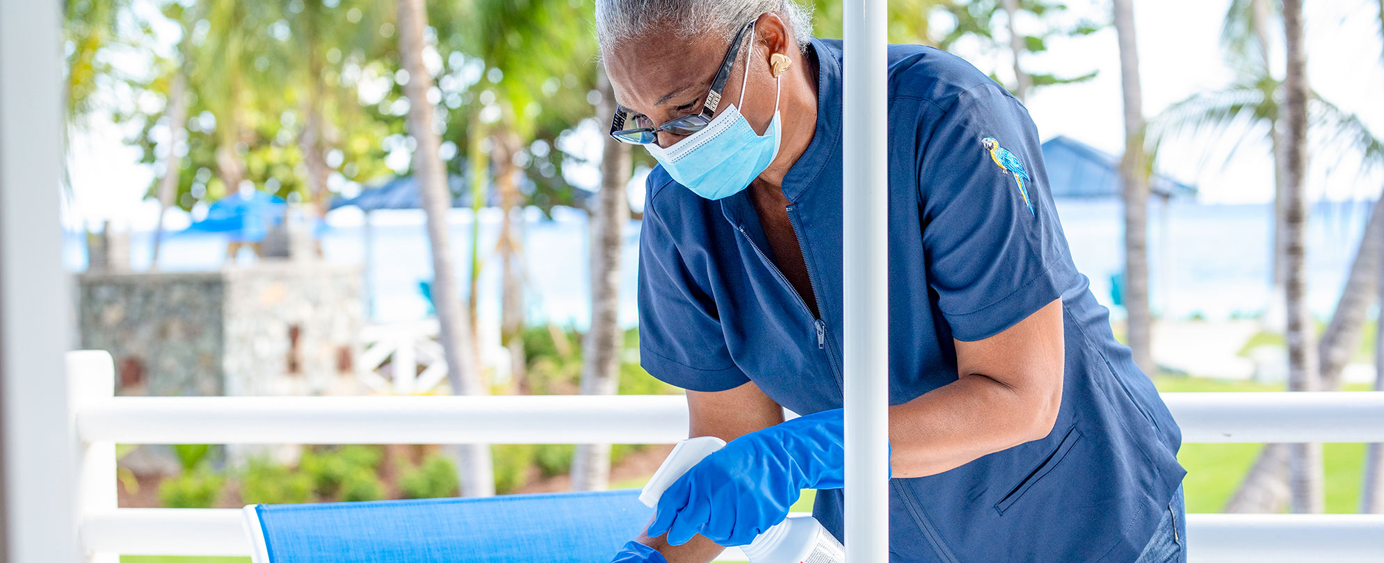 A Margaritaville Vacation Club housekeeper sanitizing outdoor seating. 