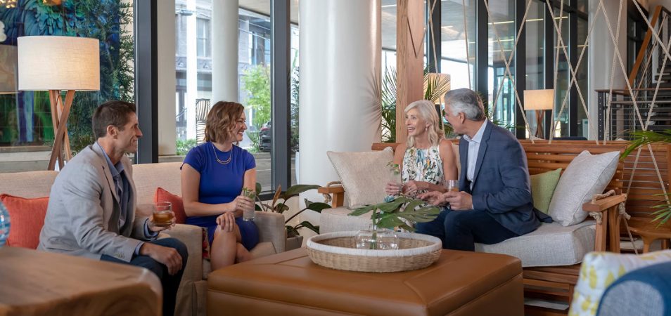 Two couples sitting at a Margaritaville Vacation Club resort lounge enjoying good conversation and a drink. 