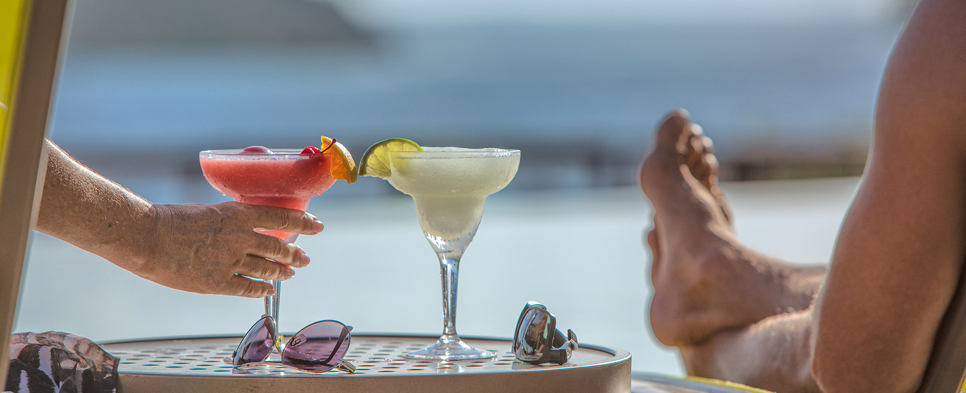 A couple laying in lounge chairs enjoying Margaritas at the resort. 