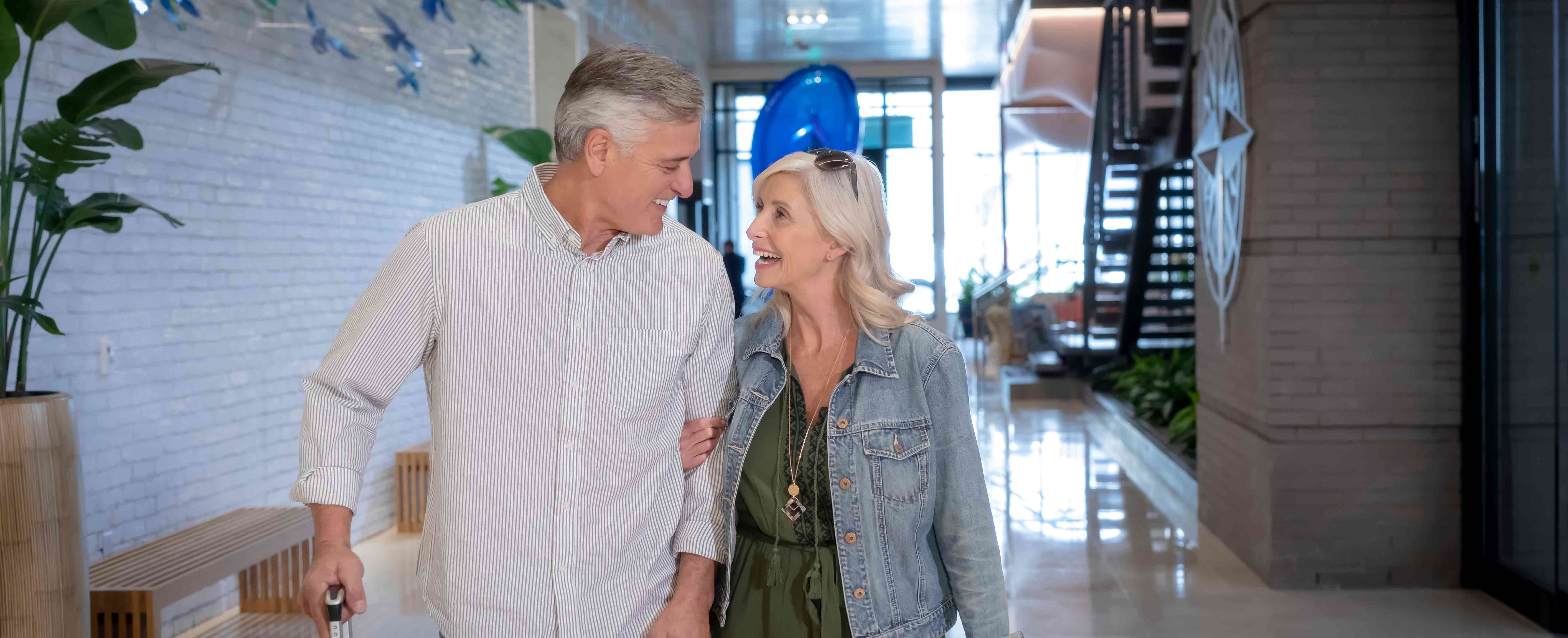 Smiling older man and woman walking through the lobby of a Margaritaville Vacation Club resort.