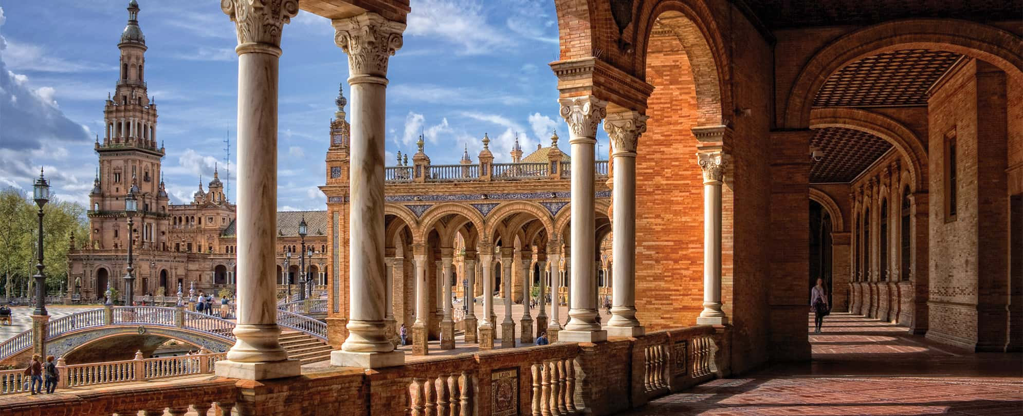 Marble columns, tall tower, and red stone architecture at the Plaza De Espana in Spain