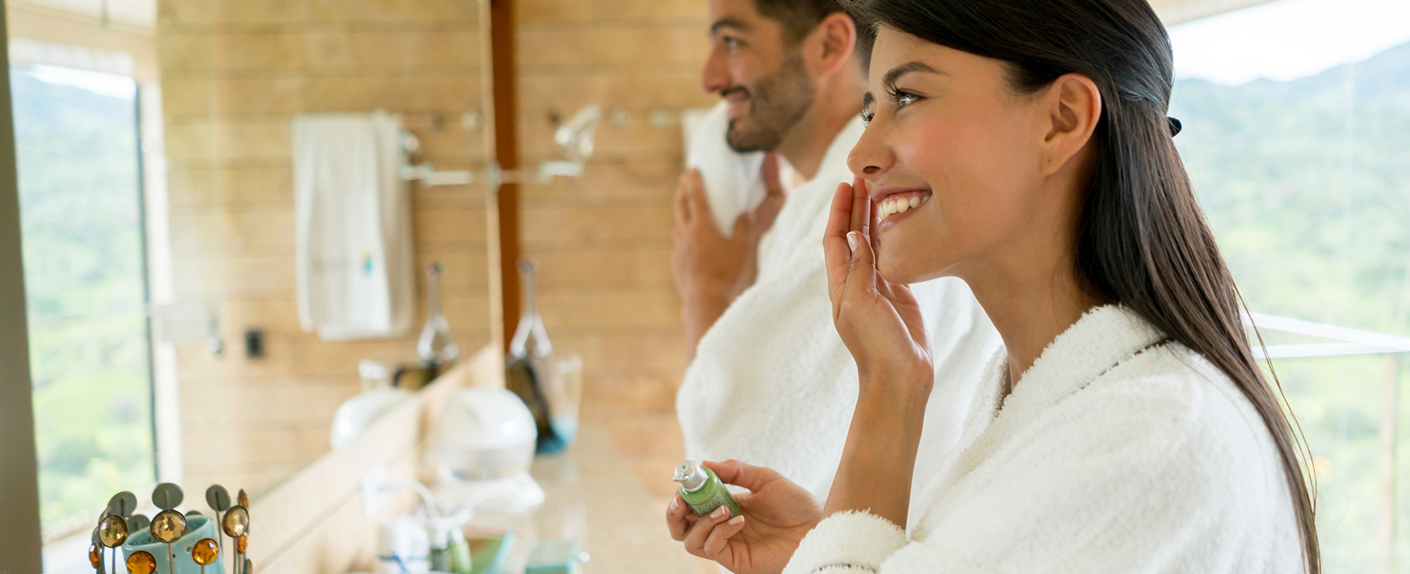  A man and woman wearing robes getting ready for the day in their resort suite bathroom.  