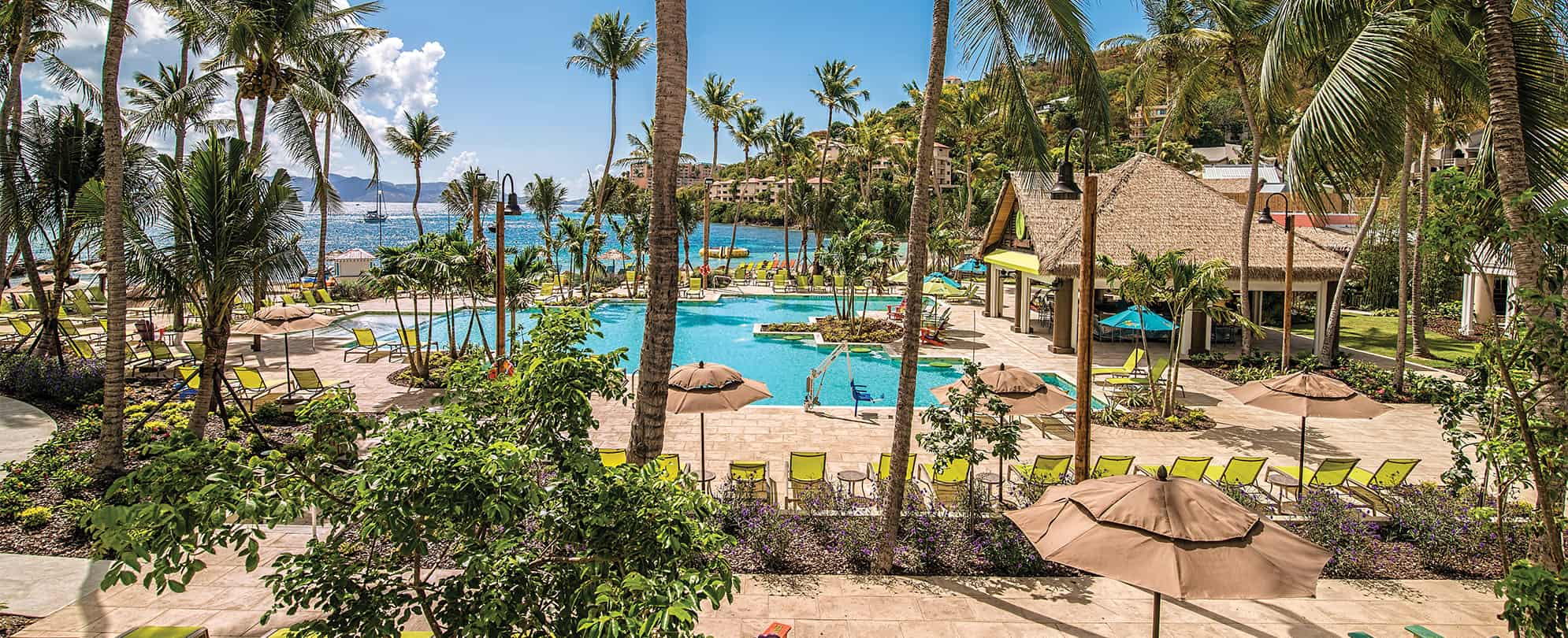 Bright green pool chairs and palm trees surround the oceanfront pool and bar at Margaritaville Vacation Club by Wyndham - St. Thomas.